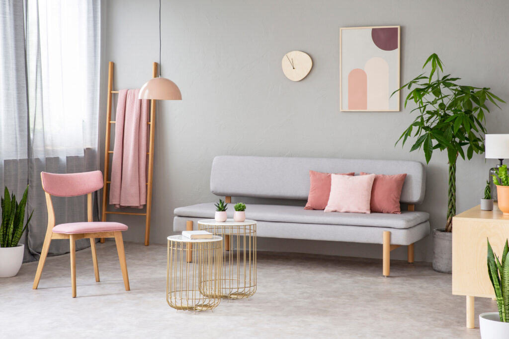 Grey sofa with pink throw pillows and gold side tables