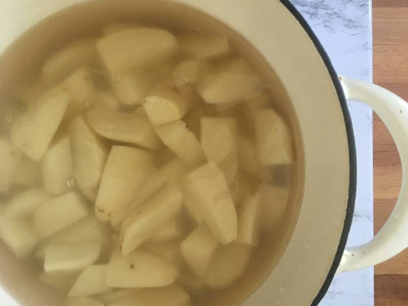 Quartered potatoes soaking in a pot to demonstrate starch content
