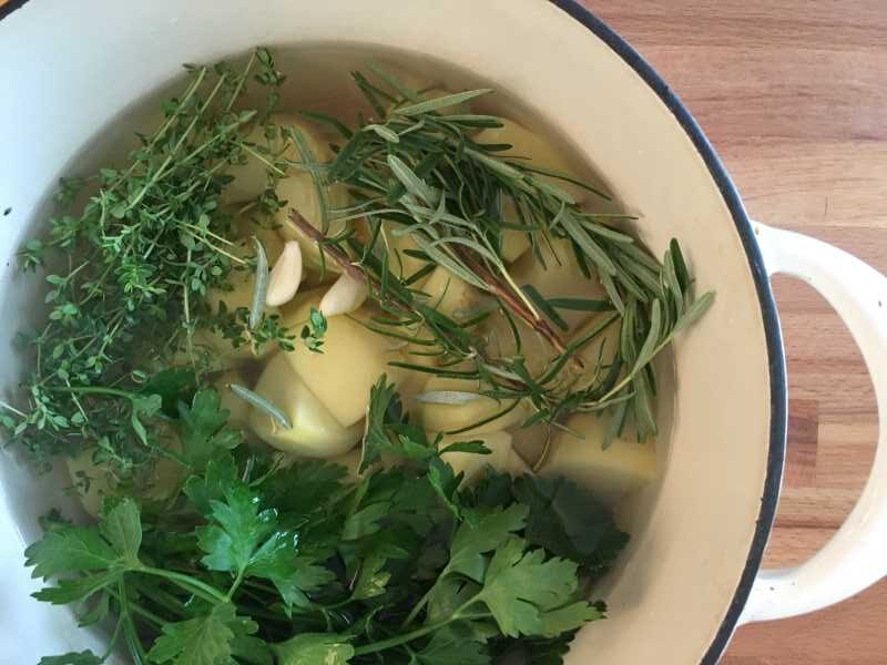 Garlic, green herbs, and potatoes in a pot