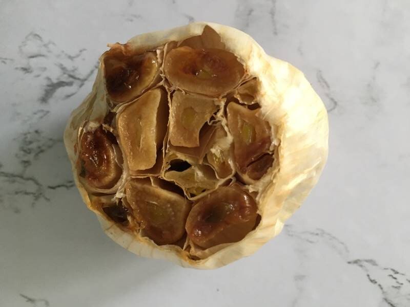 A head of caramel-colored roasted garlic in its skin
