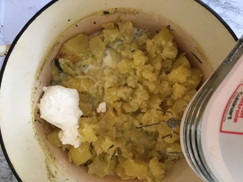 Semi-mashed potatoes in a pot with milk and sour cream