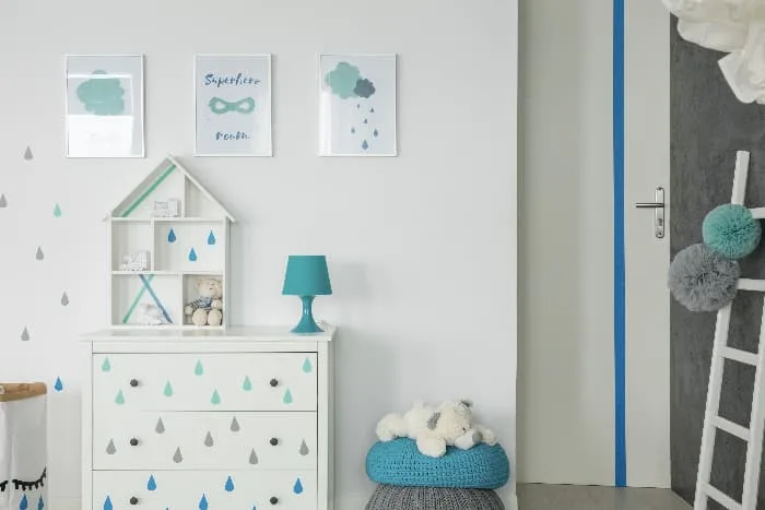 A child's room with a white painted dresser with raindrop stencils on the drawers.