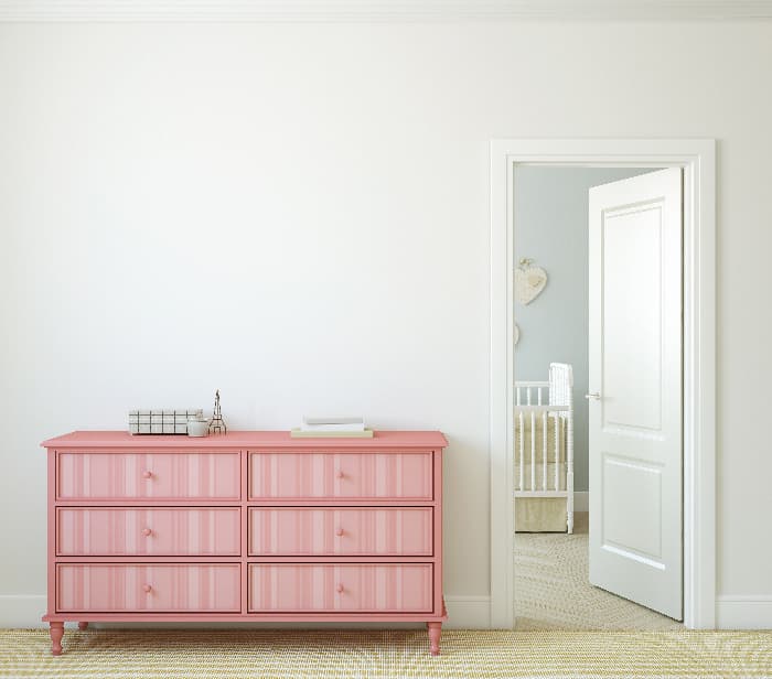 A painted dresser with a pink monochromatic pattern of vertical stripes  the drawers.