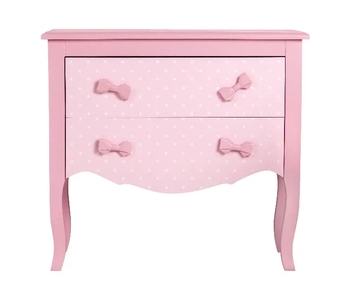 A painted dresser in two shades of lavender with knob hardware in the shape of bows and white polka dots on the front of the drawers.