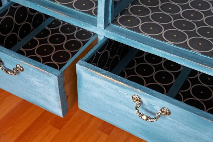 Closeup of two open drawers in a blue painted dresser with antique distressing.