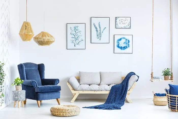 A blue furniture accent piece -- a blue armchair in a white living room that ties in various smaller blue items and blue artwork on the walls.