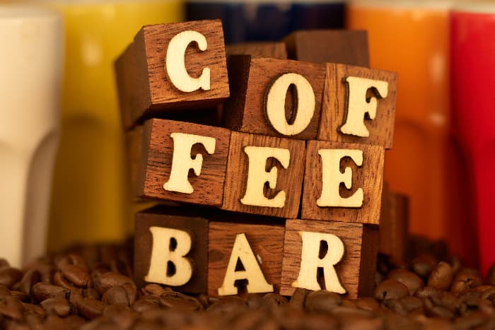 A farmhouse kitchen sign created by using wooden blocks to spell out "COFFEE BAR" by stacking the blocks on one another.