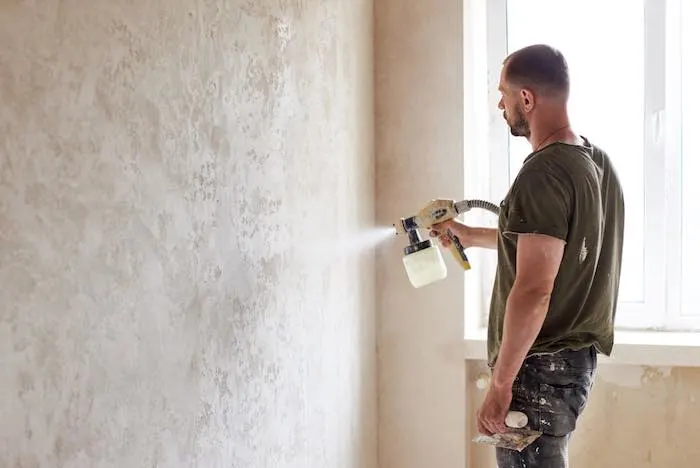 Painter working with a paint sprayer and aiming to prevent blotchy spray paint.