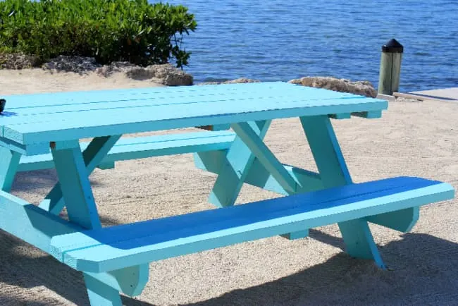 A picnic table painted a light turquoise color -- a fun and festive painted table idea.
