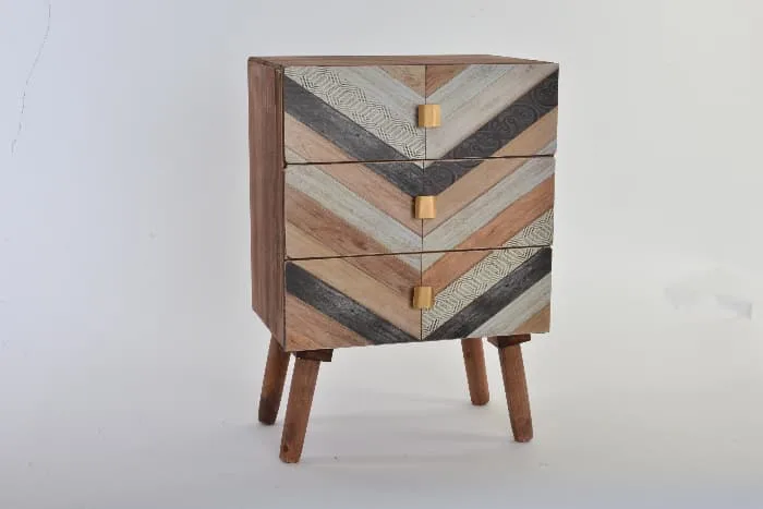 A small cupboard that has been painted to look like wood inlay in a chevron pattern -- an idea for a painted table project.