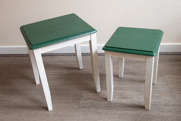 Two small end tables with the tops painted green and the table base and legs painted white -- a simple painted table design.