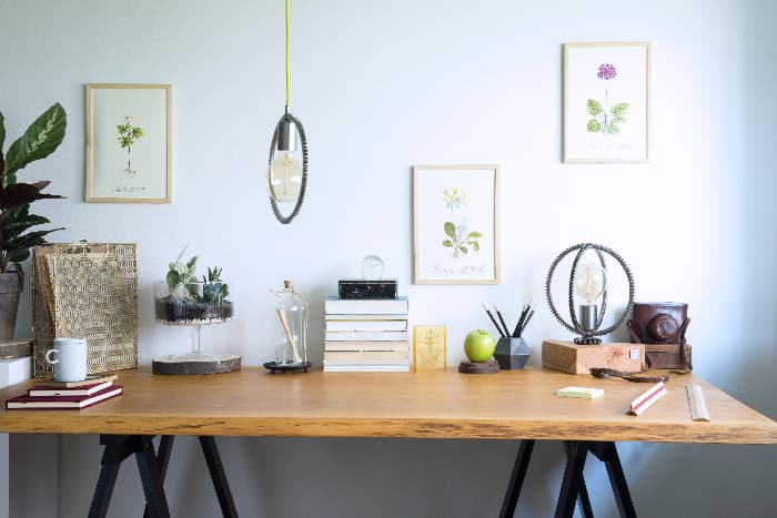 Farmhouse desk made of solid wood piece on black sawhorses against blue wall.