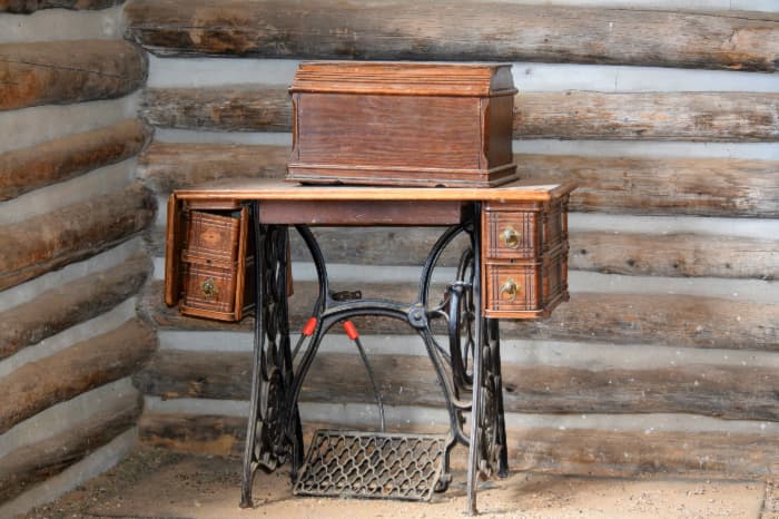 Desk made from antique sewing machine table against log cabin wall.