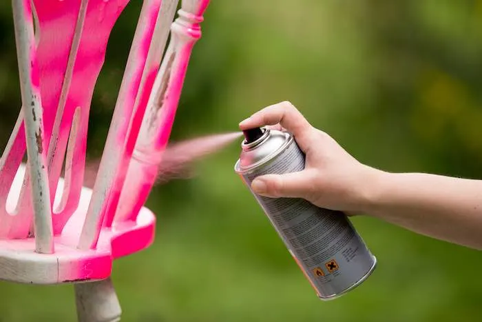 Spray painting an old chair in the color pink, while avoiding blotchy spray paint.