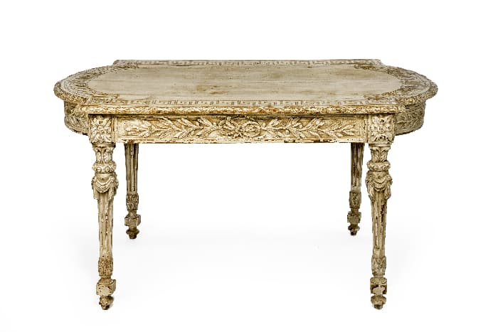 An ornate white painted table with distressing and the antique patina effect that stain over paint produces.