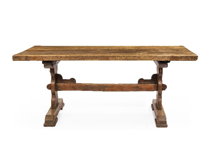 Medium wood-stain trestle table serving as a farmhouse desk.