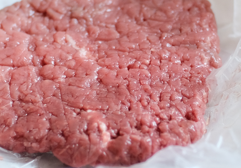 A closeup of raw cube steak on butcher paper.