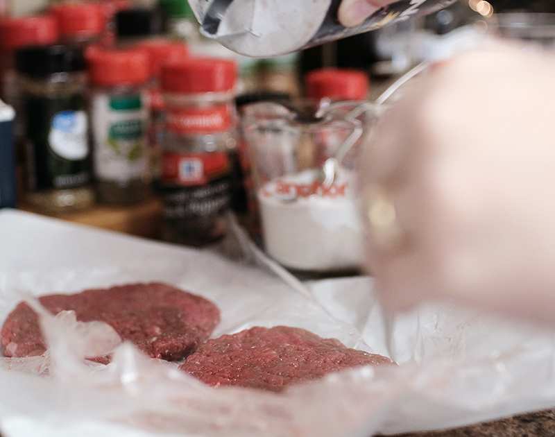 Closeup of hands salting pieces of cube steak.
