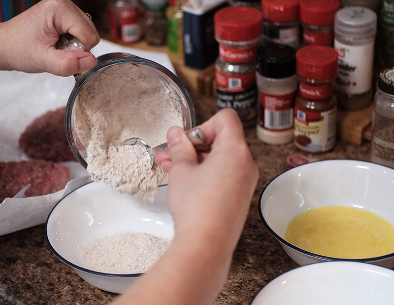 Closeup of spiced flour being spooned into a bowl.