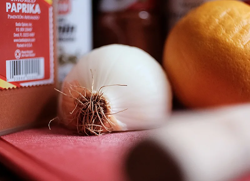 Section of onion and a lemon on a red cutting board