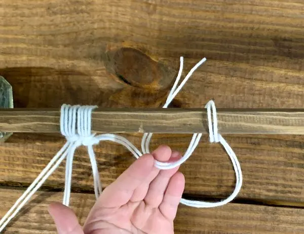 Tieing a larks head knot with the final strand of yarn.