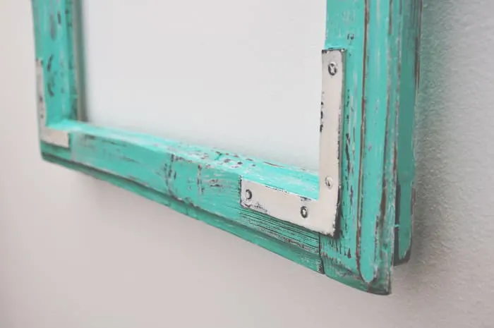 Closeup of bottom edge of painted picture or cabinet frame with distressing. When you know how to chalk paint furniture, you can apply that knowledge other paint projects.