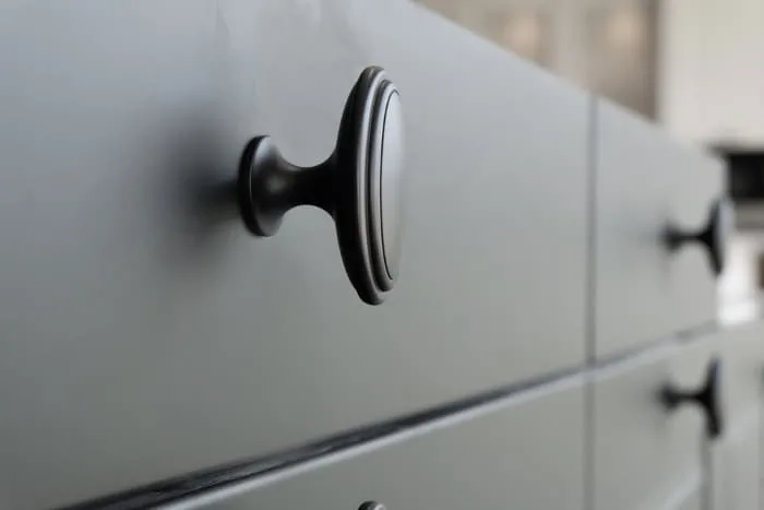 Closeup of a modern dresser and knobs with a matte gray paint finish. Knowing how to get a smooth finish with chalk paint opens the door all sorts of paint projects.