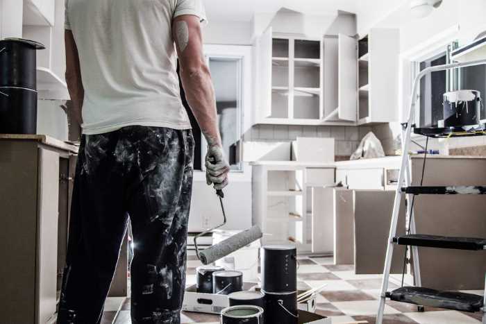A man standing in a kitchen, prepared for cabinet painting