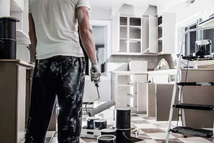A man standing in a kitchen, prepared for cabinet painting