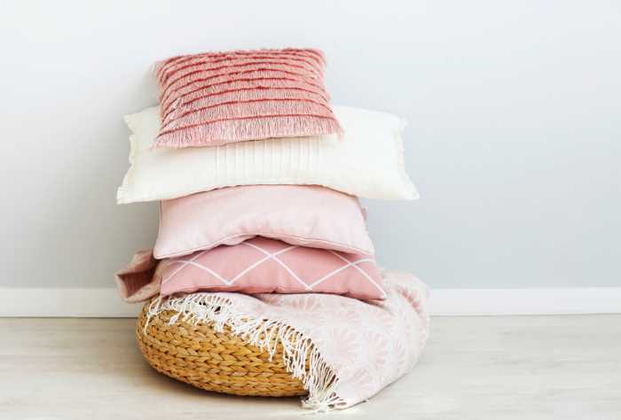 pink pillows stacked in a woven basket