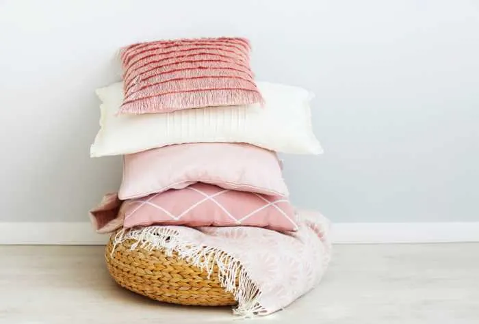 pink pillows stacked in a woven basket