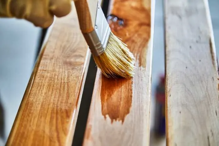 applying varnish to a wood project with a brush