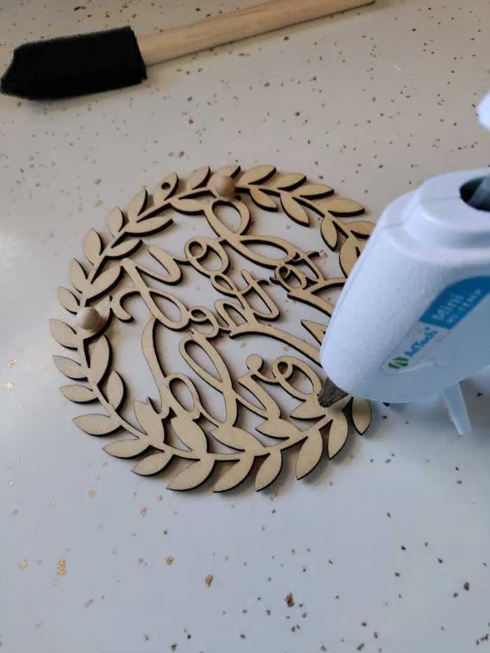 use a hot glue gun to glue the beads to the back of your wooden ornament.