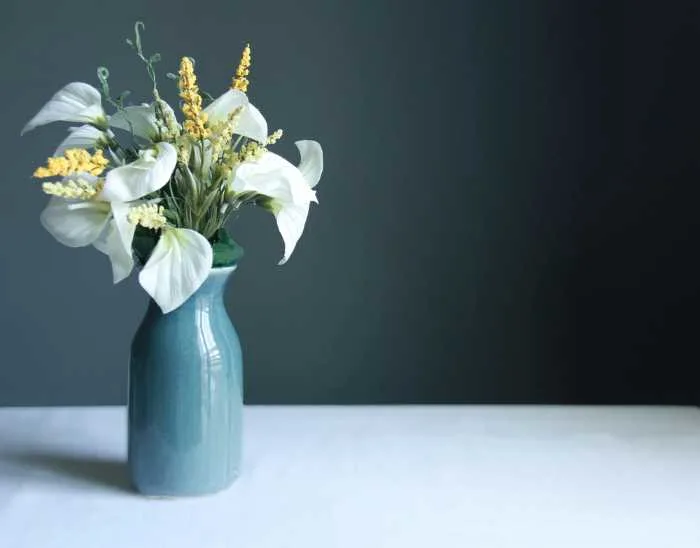 teal vase with calla lilies in it