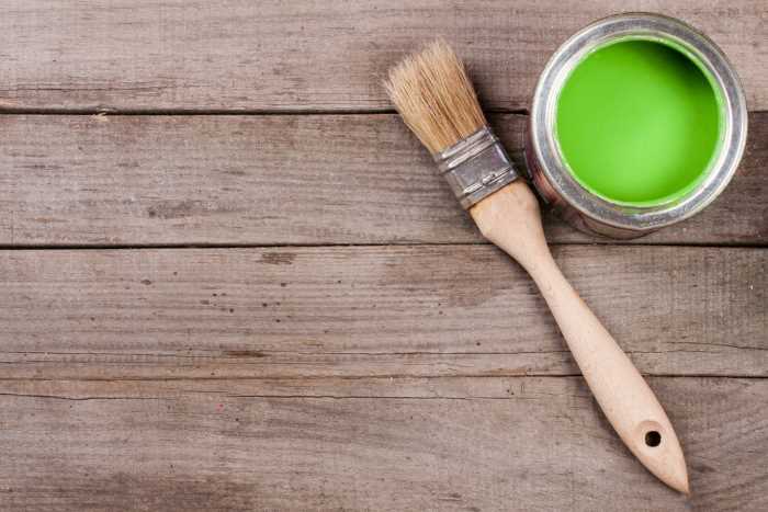 can of green chalk paint with a paint brush laying beside it