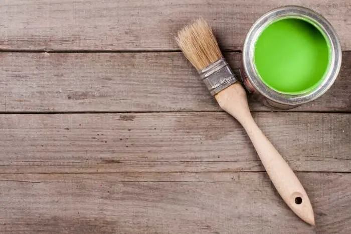 can of green chalk paint with a paint brush laying beside it