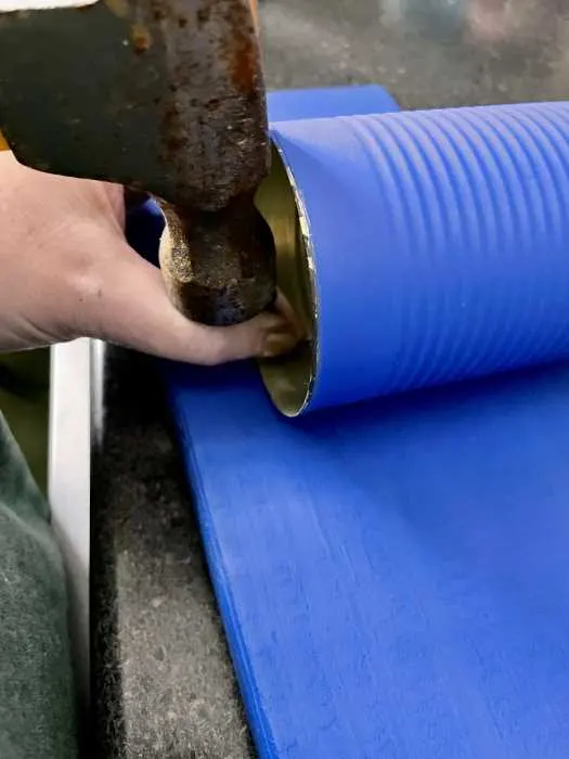 hammering a hole into the can