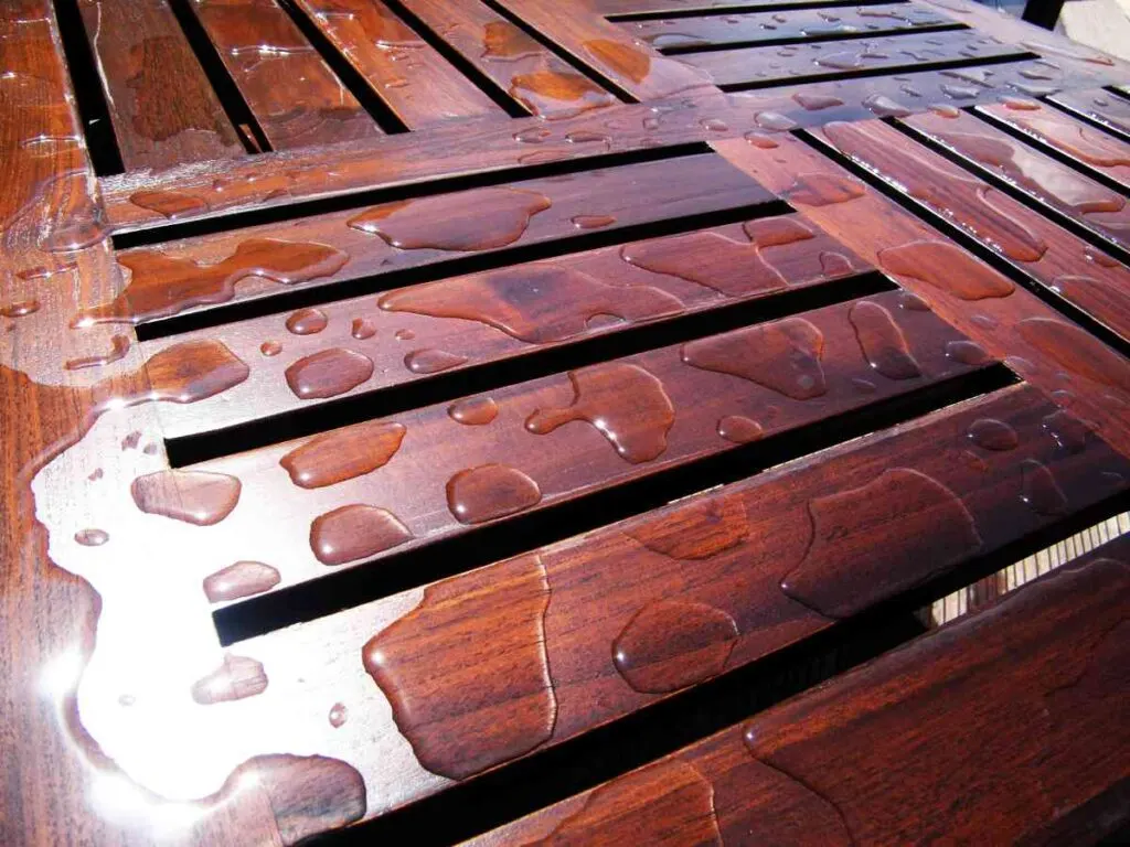 Water droplets beading on stained outdoor wood table