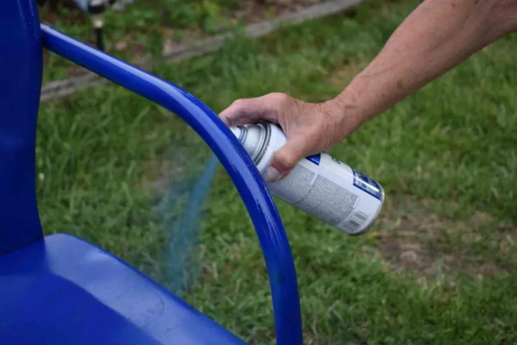 Using spray paint to paint a metal chair blue