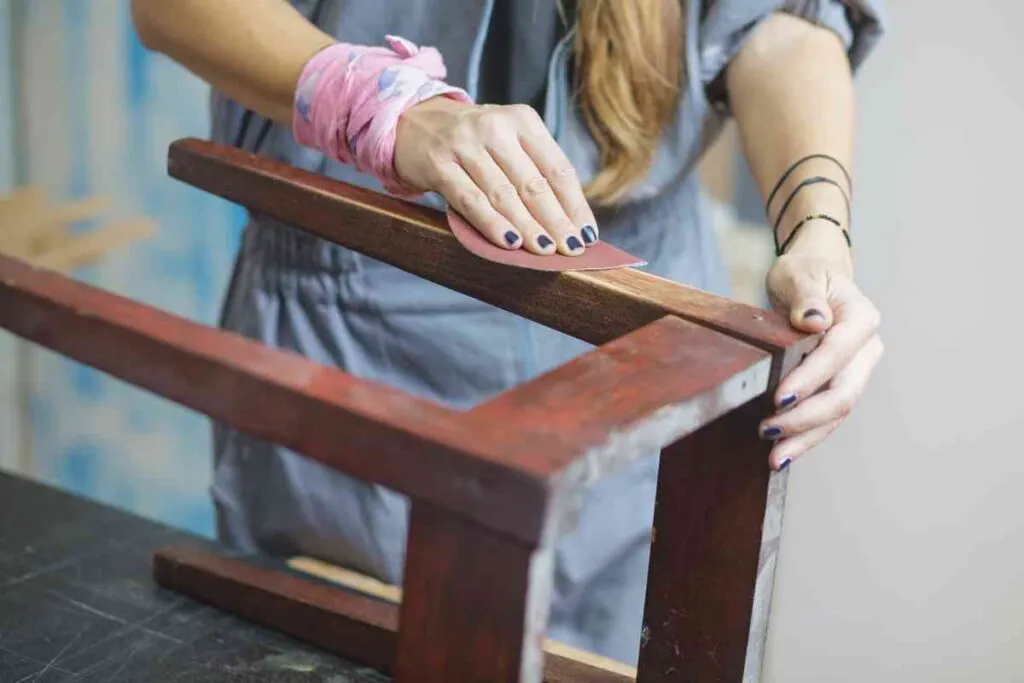 Woman sanding polyurethane off an old wooden chair
