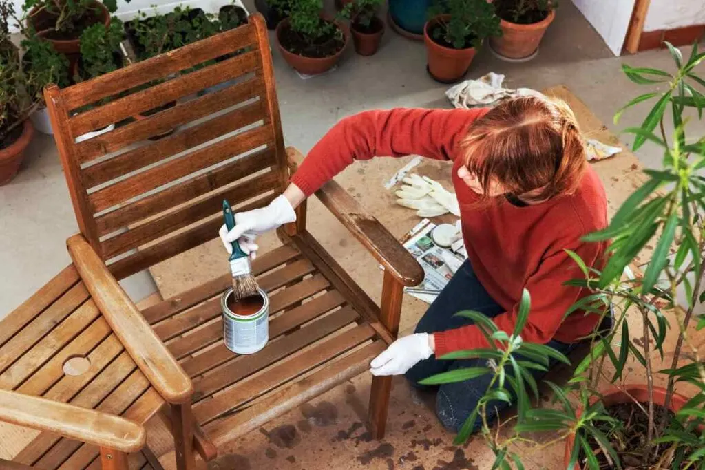 Woman showing how to seal outdoor wood furniture with sealant and brush