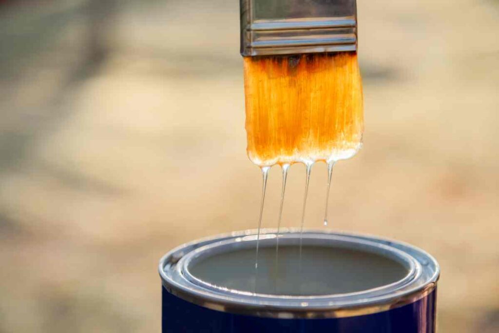 A paintbrush and can of polyurethane