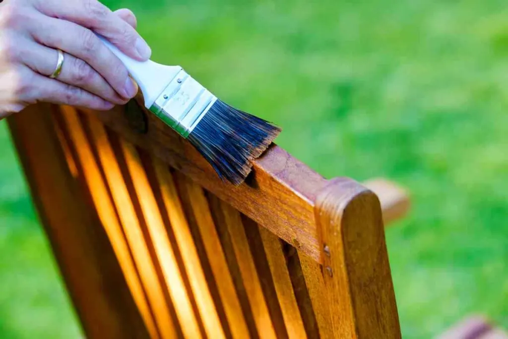 Using a brush to apply sealer to a wooden chair