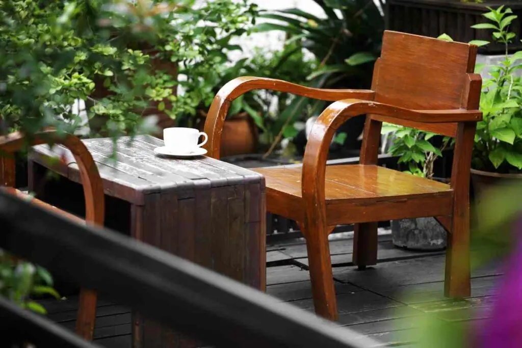 Wooden outdoor table and chair with green foliage background