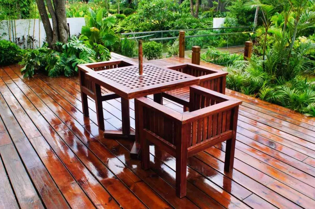 Outdoor table and chairs on a wood deck, wet from the rain