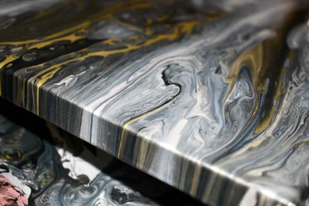 Black, gold, and grey paint poured canvas drying