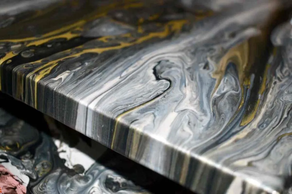 Black, gold, and grey paint poured canvas drying