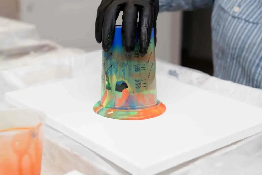 Paint pouring by layering colors in a cup and turning it upside on a canvas