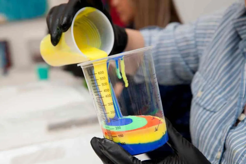 Layering colors of paint in a pour cup for pour painting technique