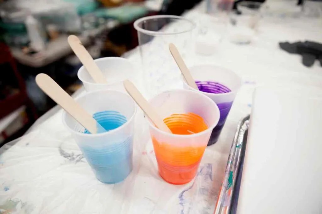 Mixing blue, orange, and purple paints with medium for paint pouring